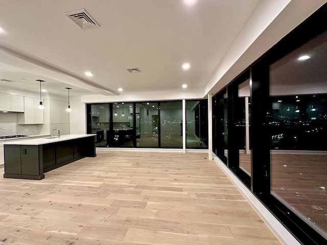 kitchen featuring light wood finished floors, a sink, visible vents, and white cabinetry