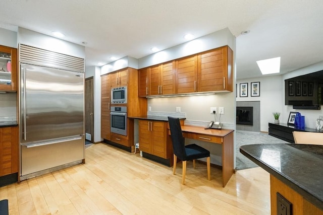 21 Birch Ln, Northampton, MA 01062 - kitchen with built in appliances, a skylight, light wood-style flooring, brown cabinets, and recessed lighting