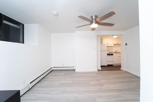 empty room featuring ceiling fan, a textured ceiling, light wood-type flooring, and baseboard heating