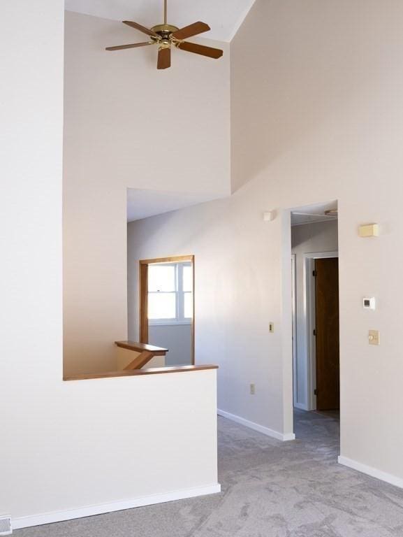 carpeted spare room featuring ceiling fan and high vaulted ceiling