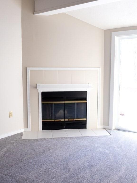 interior details featuring beamed ceiling, a tiled fireplace, and carpet flooring