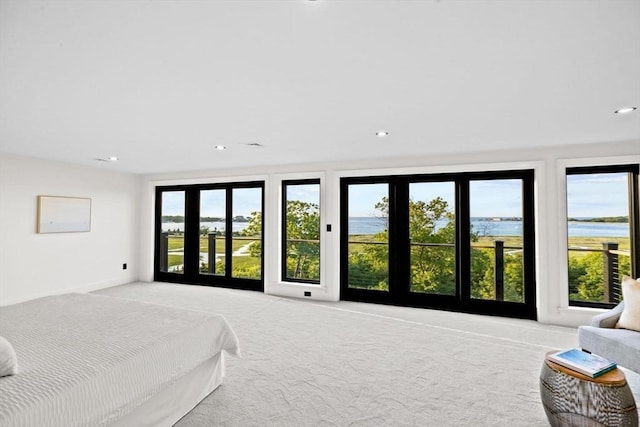 bedroom with a water view and light carpet