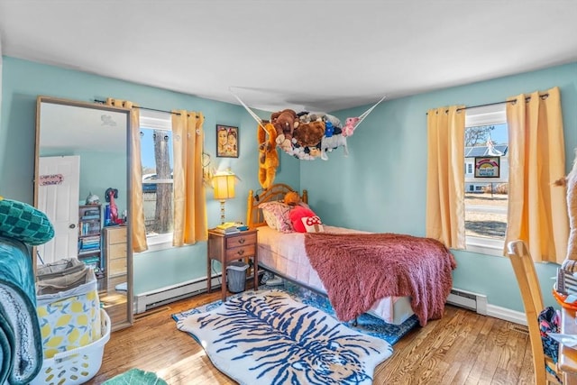 bedroom with a baseboard radiator, baseboards, baseboard heating, and wood finished floors