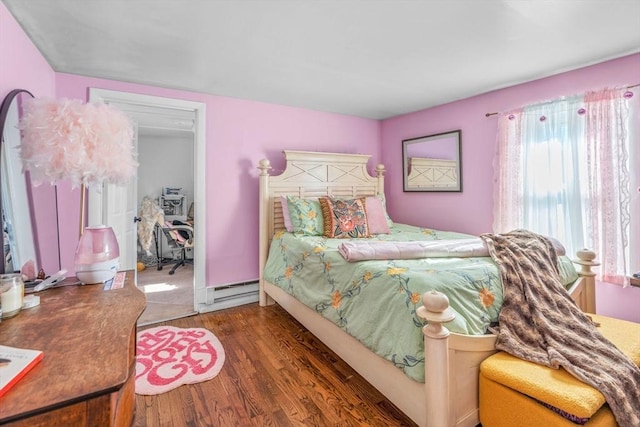 bedroom featuring a closet, a baseboard heating unit, and wood finished floors