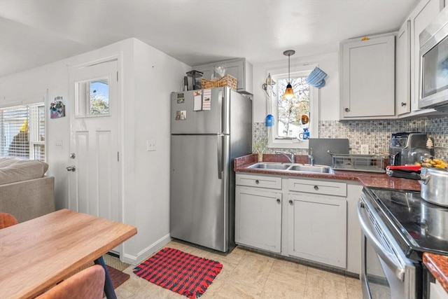 kitchen with appliances with stainless steel finishes, dark countertops, a sink, and decorative backsplash