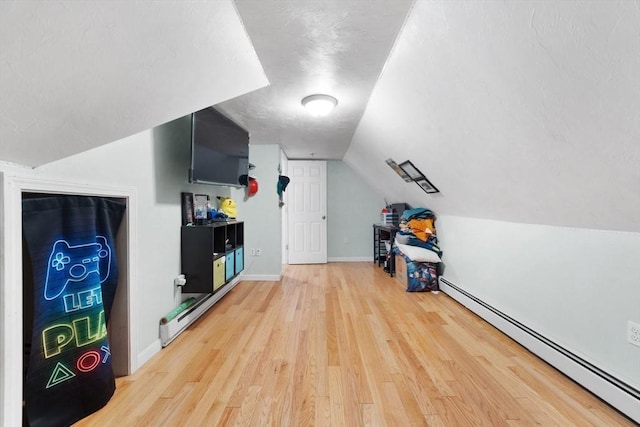 additional living space featuring vaulted ceiling, wood-type flooring, and baseboard heating