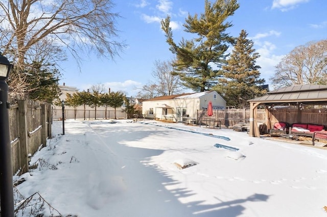 yard layered in snow featuring a gazebo and an outbuilding