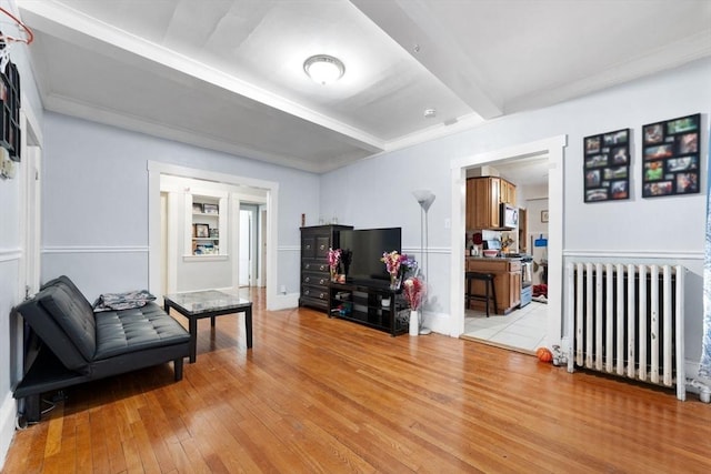 living area with beamed ceiling, radiator, and light hardwood / wood-style flooring