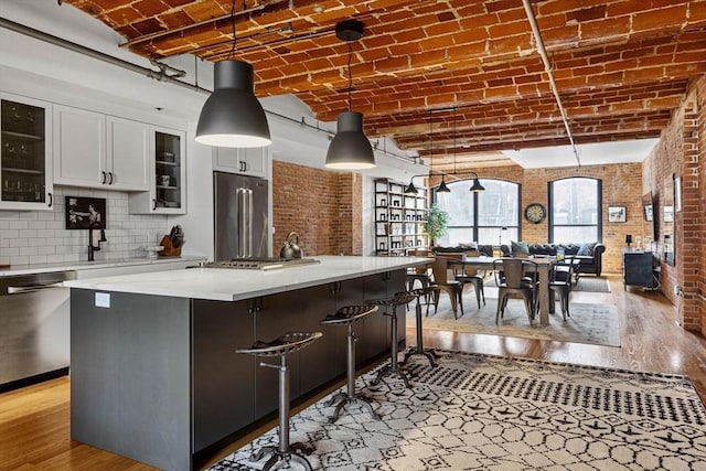 121-123 Beach St Unit 603, Boston, MA 02111 - kitchen with appliances with stainless steel finishes, brick ceiling, light wood-style flooring, brick wall, and white cabinets