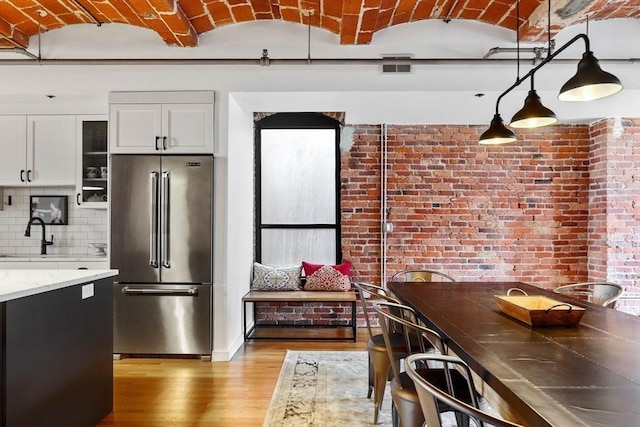 121-123 Beach St Unit 603, Boston, MA 02111 - kitchen with high end refrigerator, light wood-style flooring, a sink, white cabinets, and glass insert cabinets