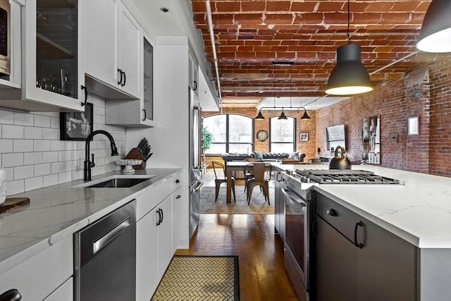 121-123 Beach St Unit 603, Boston, MA 02111 - kitchen featuring stainless steel appliances, a sink, light stone counters, glass insert cabinets, and brick ceiling