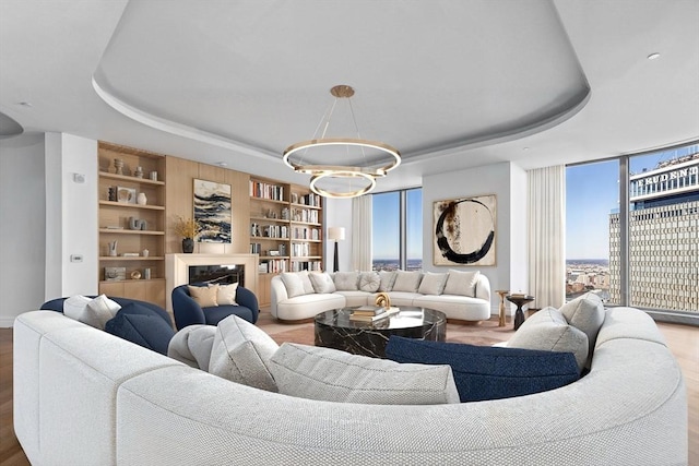 living room featuring built in features, wood-type flooring, and a tray ceiling