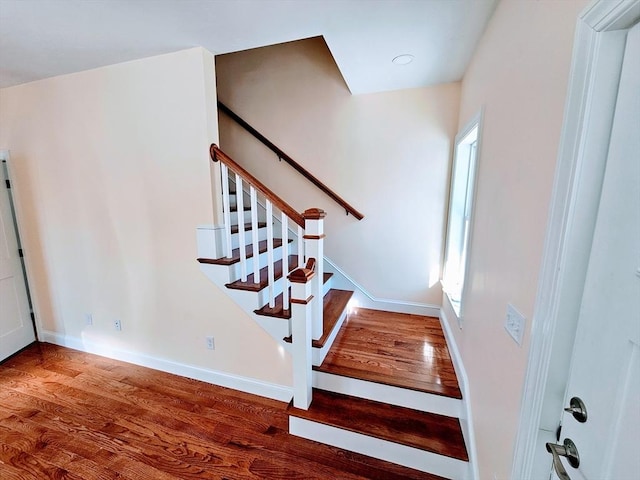 stairway featuring a healthy amount of sunlight, baseboards, and wood finished floors