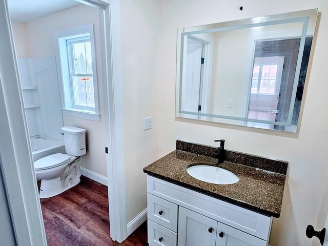 full bathroom featuring toilet, wood finished floors, vanity, baseboards, and washtub / shower combination