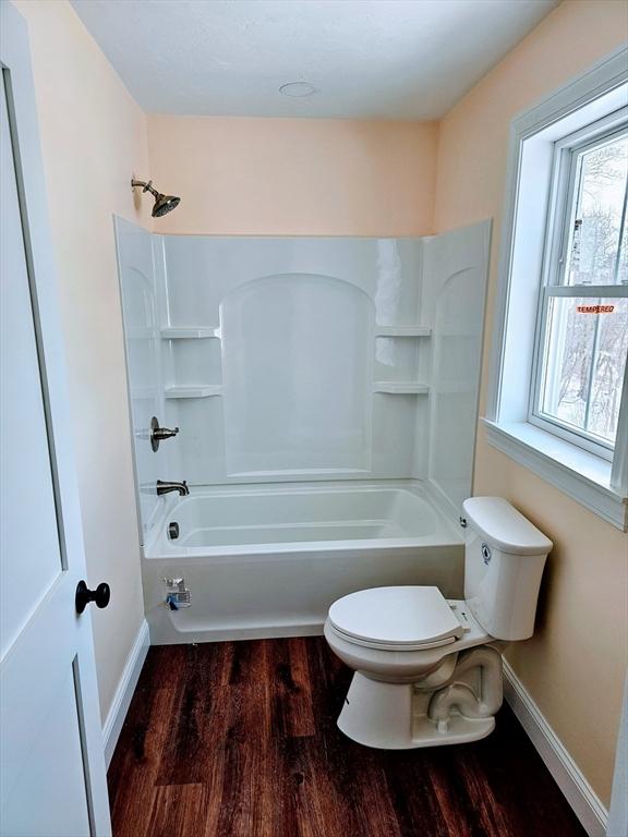 full bath with shower / washtub combination, baseboards, toilet, and wood finished floors