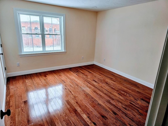 empty room featuring baseboards and dark wood finished floors