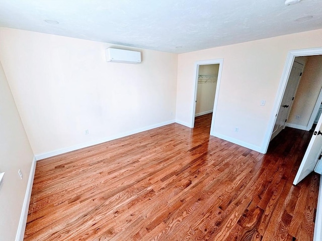 interior space with an AC wall unit, wood finished floors, and baseboards