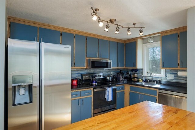 kitchen featuring a sink, blue cabinetry, backsplash, and appliances with stainless steel finishes