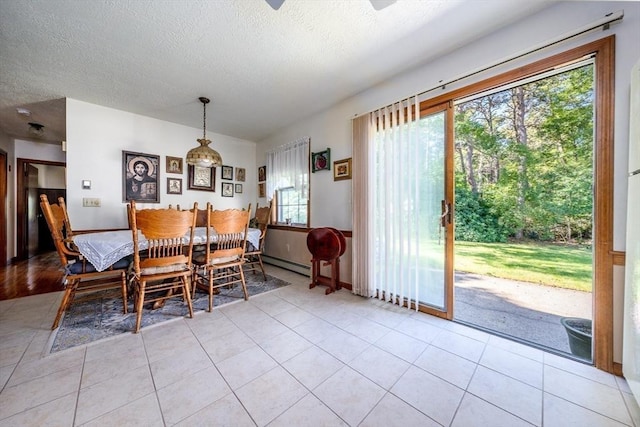 dining room with light tile patterned floors, a textured ceiling, a baseboard radiator, and a wealth of natural light