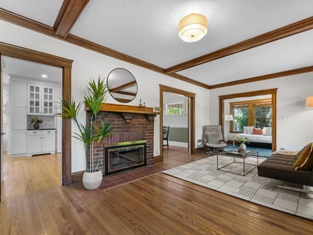 161 Playstead Rd, Medford, MA 02155 - living area featuring wood finished floors, a brick fireplace, beam ceiling, and crown molding