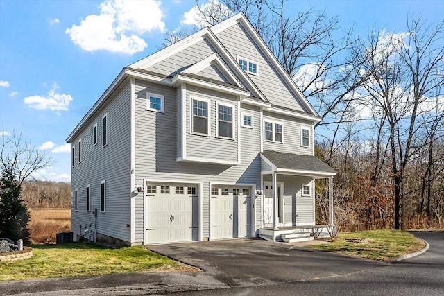 view of front of property featuring cooling unit, a garage, and a front lawn