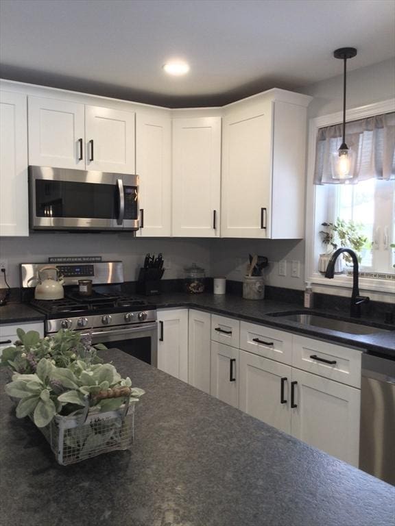 kitchen with white cabinetry, appliances with stainless steel finishes, sink, and pendant lighting