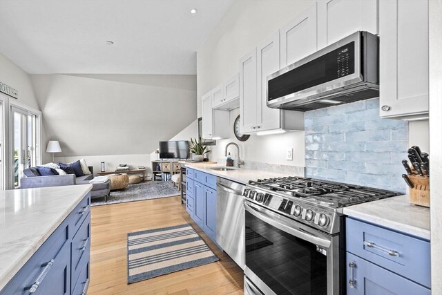 646 Jerusalem Rd Unit 7, Cohasset, MA 02025 - kitchen with stainless steel appliances, a sink, blue cabinetry, lofted ceiling, and open floor plan