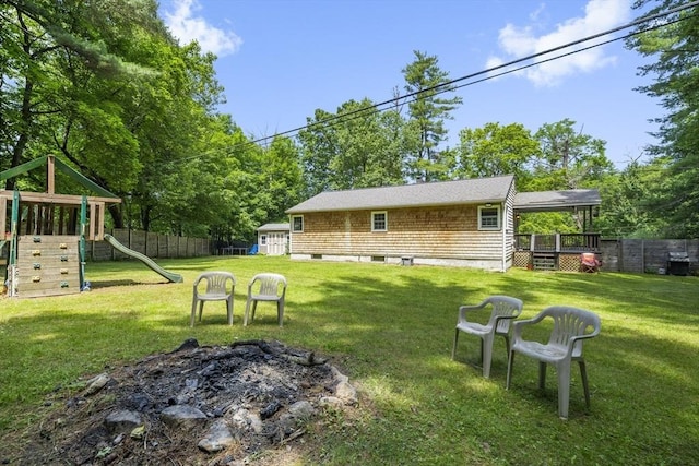 255 State St, Belchertown, MA 01007 - fenced backyard featuring a playground, a storage shed, a fire pit, and a wooden deck