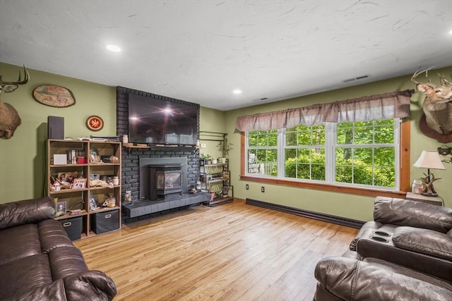 255 State St, Belchertown, MA 01007 - living area with wood finished floors, recessed lighting, a wood stove, and a baseboard heating unit