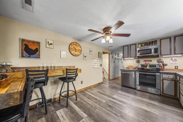 255 State St, Belchertown, MA 01007 - kitchen featuring stainless steel appliances, ceiling fan, dark wood-style flooring, a breakfast bar, and a peninsula