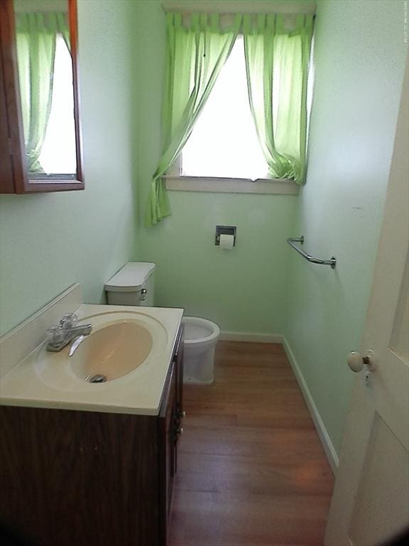 39 King St, Holyoke, MA 01040 - half bathroom featuring vanity, toilet, baseboards, and wood finished floors