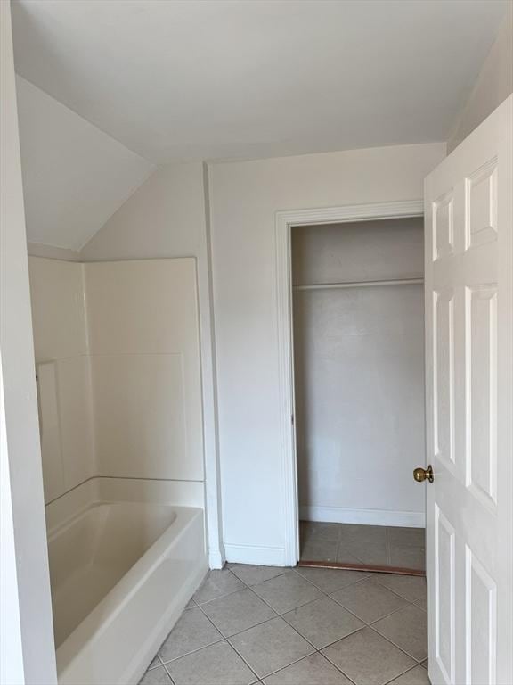 bathroom featuring lofted ceiling, tile patterned floors, and washtub / shower combination