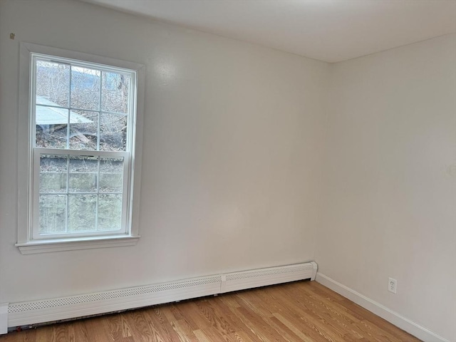 spare room featuring a baseboard radiator and light hardwood / wood-style floors