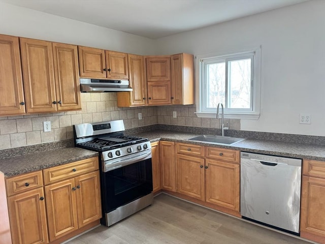 kitchen with sink, backsplash, stainless steel appliances, and light wood-type flooring