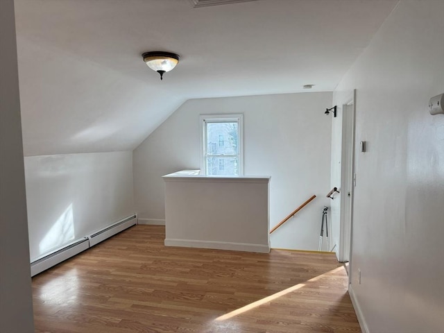 bonus room featuring hardwood / wood-style flooring, vaulted ceiling, and a baseboard heating unit