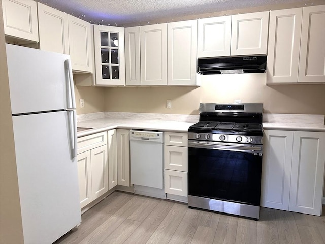 kitchen with light wood-type flooring, a textured ceiling, white appliances, and white cabinetry