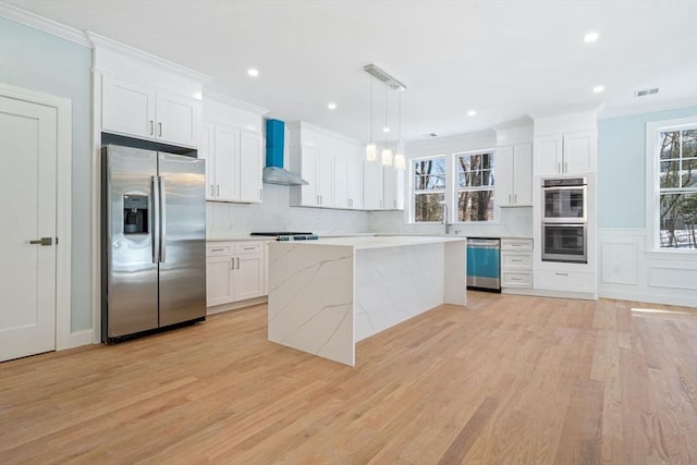 kitchen with stainless steel appliances, visible vents, white cabinetry, wall chimney range hood, and crown molding