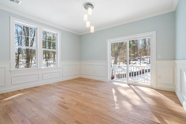 unfurnished dining area with light wood-style floors, a healthy amount of sunlight, and ornamental molding