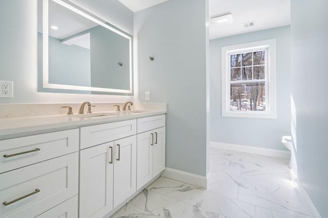 bathroom with toilet, vanity, visible vents, baseboards, and marble finish floor