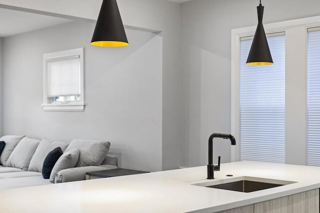 kitchen featuring light countertops, open floor plan, hanging light fixtures, and a sink