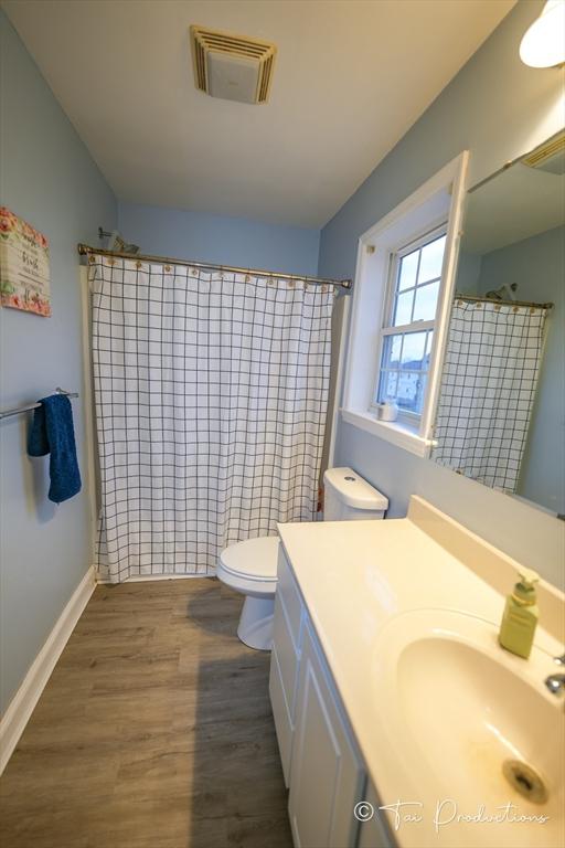 115 Arnold St, Fall River, MA 02724 - full bath featuring wood finished floors, toilet, curtained shower, vanity, and visible vents