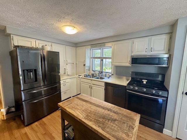 39 Pine Grove Rd, Yarmouth, MA 02664 - kitchen featuring appliances with stainless steel finishes, a sink, light wood-type flooring, white cabinetry, and a textured ceiling
