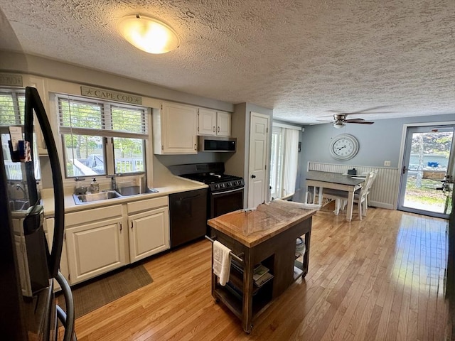 39 Pine Grove Rd, Yarmouth, MA 02664 - kitchen featuring a sink, black appliances, white cabinetry, a textured ceiling, and light wood-style floors