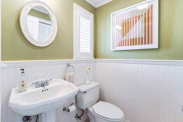 bathroom with a sink, wainscoting, toilet, and ornamental molding