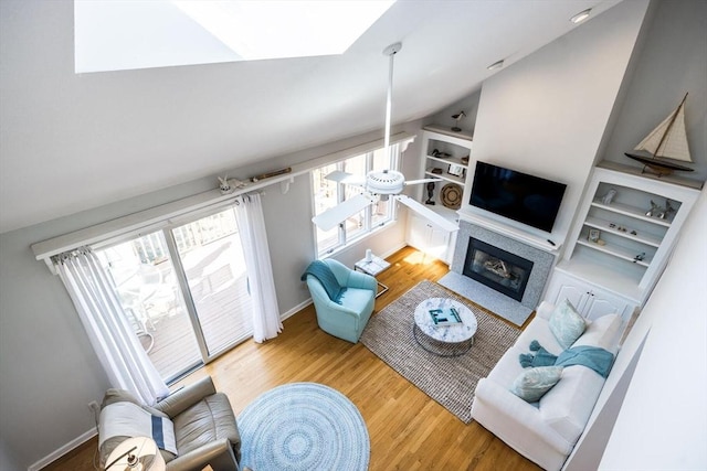 living area featuring baseboards, a fireplace with flush hearth, built in features, and wood finished floors
