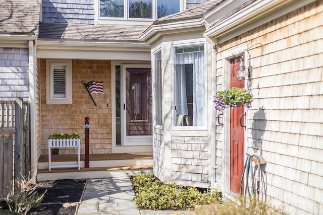 view of exterior entry with a shingled roof