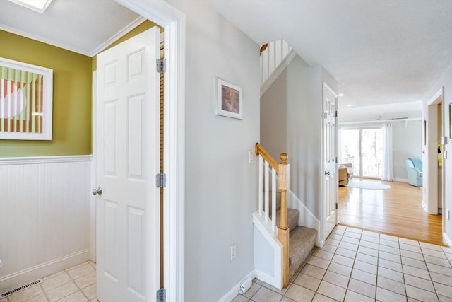hall with baseboards, visible vents, light tile patterned floors, and stairway