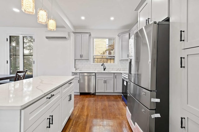 kitchen featuring decorative backsplash, appliances with stainless steel finishes, light stone counters, decorative light fixtures, and an AC wall unit