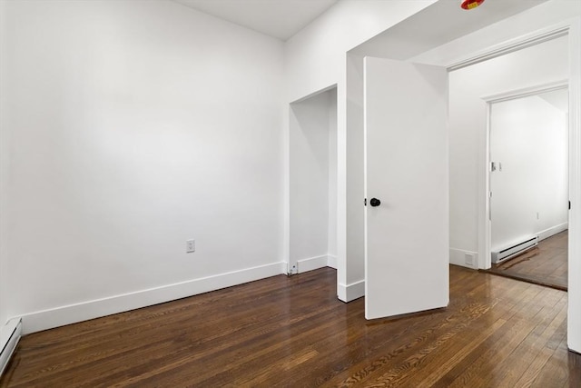 empty room featuring baseboard heating and dark wood-type flooring