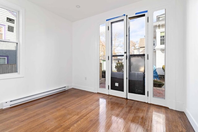 empty room with hardwood / wood-style flooring and baseboard heating